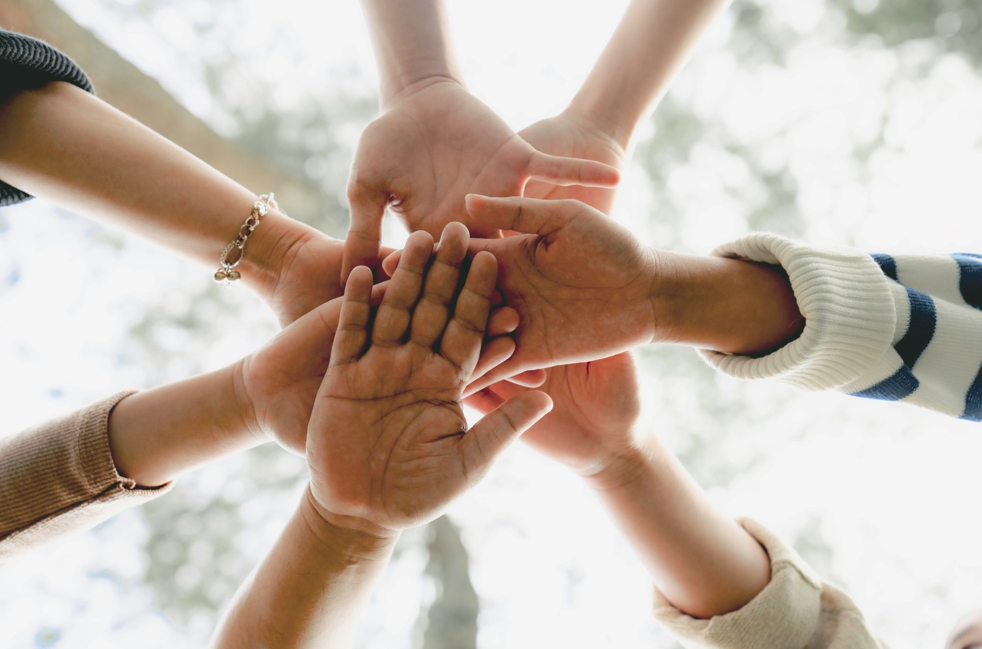 Horizonte e.V. Gemeinschaft Fünf Hände verschiedener Hautfarben liegen übereinander in der Mitte.